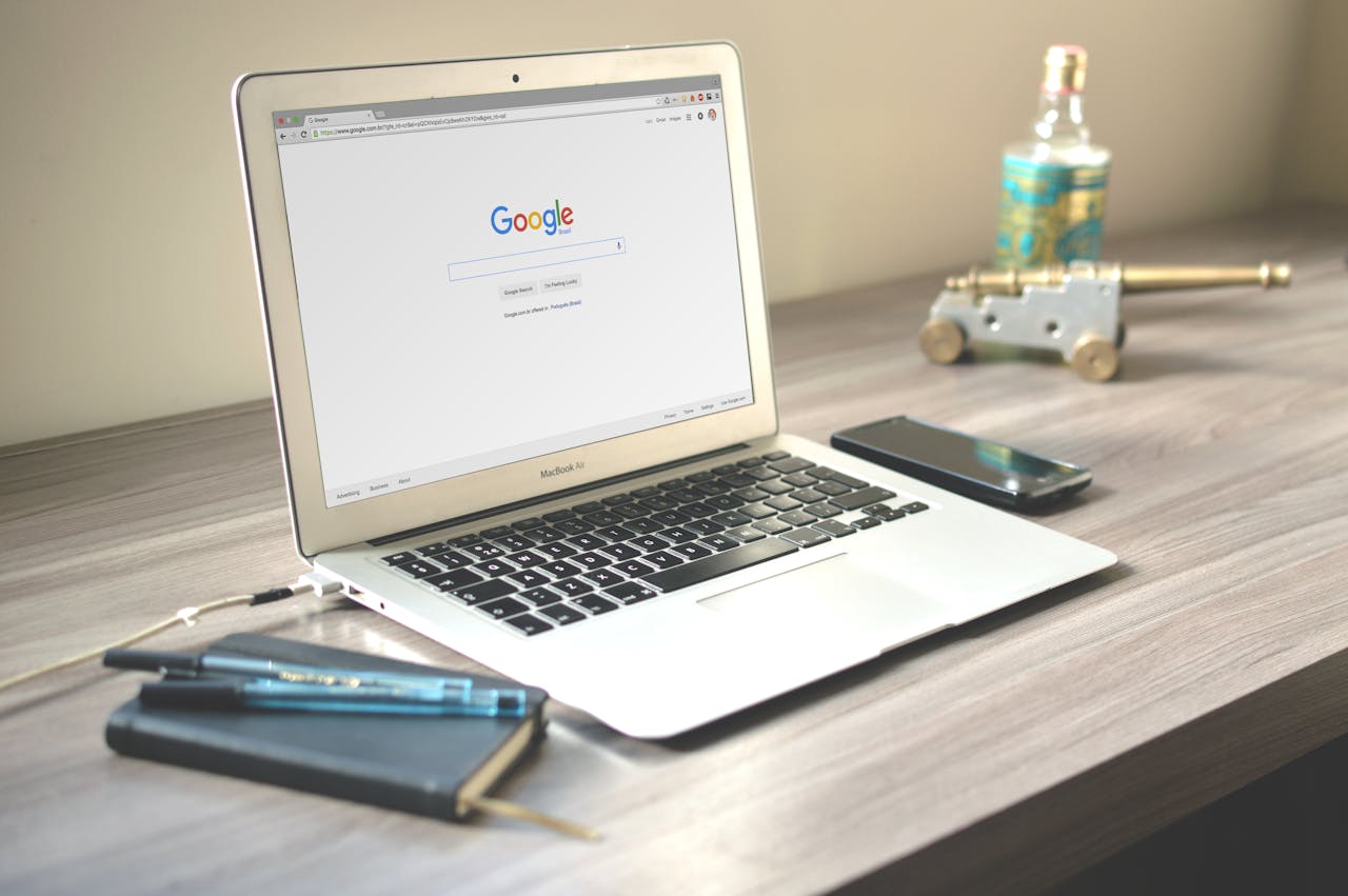 Mastering the First Impression: Your intriguing post title goes here A neat workspace featuring a laptop displaying Google search, a smartphone, and a notebook on a wooden desk.
