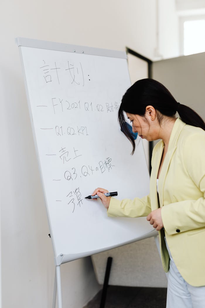 Crafting Captivating Headlines: Your awesome post title goes here Asian businesswoman writing on a whiteboard during a presentation in a corporate setting.